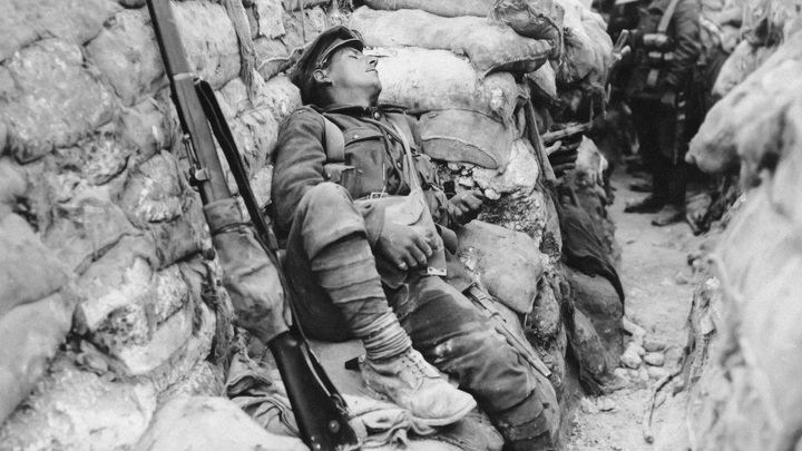 A soldier from WWI tries to sleep in the trenches in a nest of sandbags