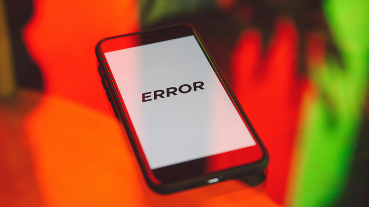 Black Smartphone on table reading "Error" in black text on a white background.